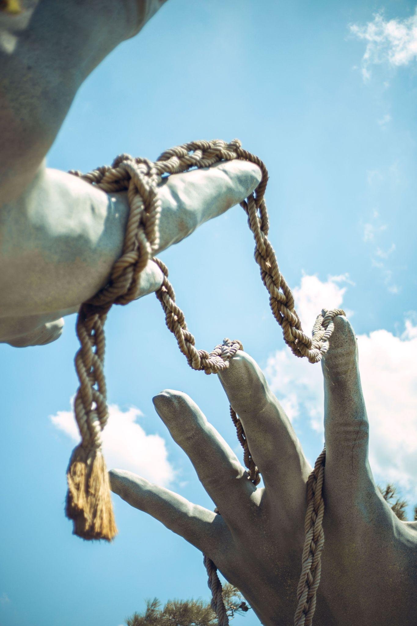 Sculpture of hands releasing a rope into the sky, representing freedom and connection